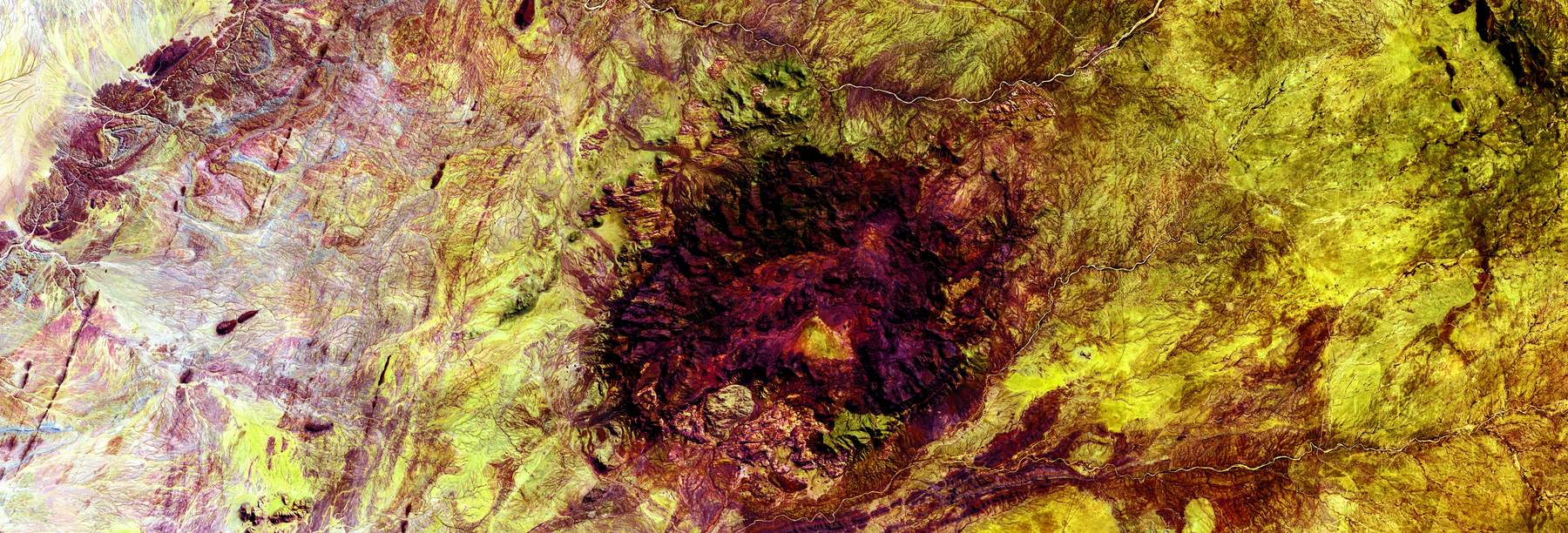 False-color aerial image of an impact structure in ochre terrain.